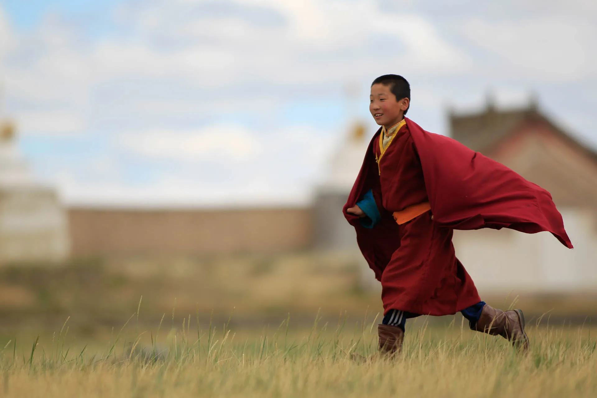 Młody mnich buddyjski w Mongolii w tradycyjnej czerwonej szacie