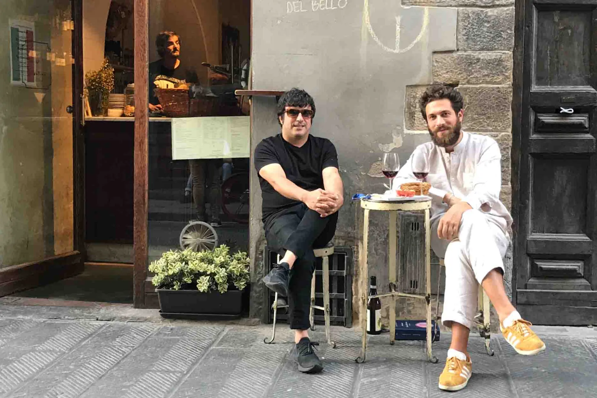 Dwaj mężczyźni piją wino przy małym stoliku na ulicy