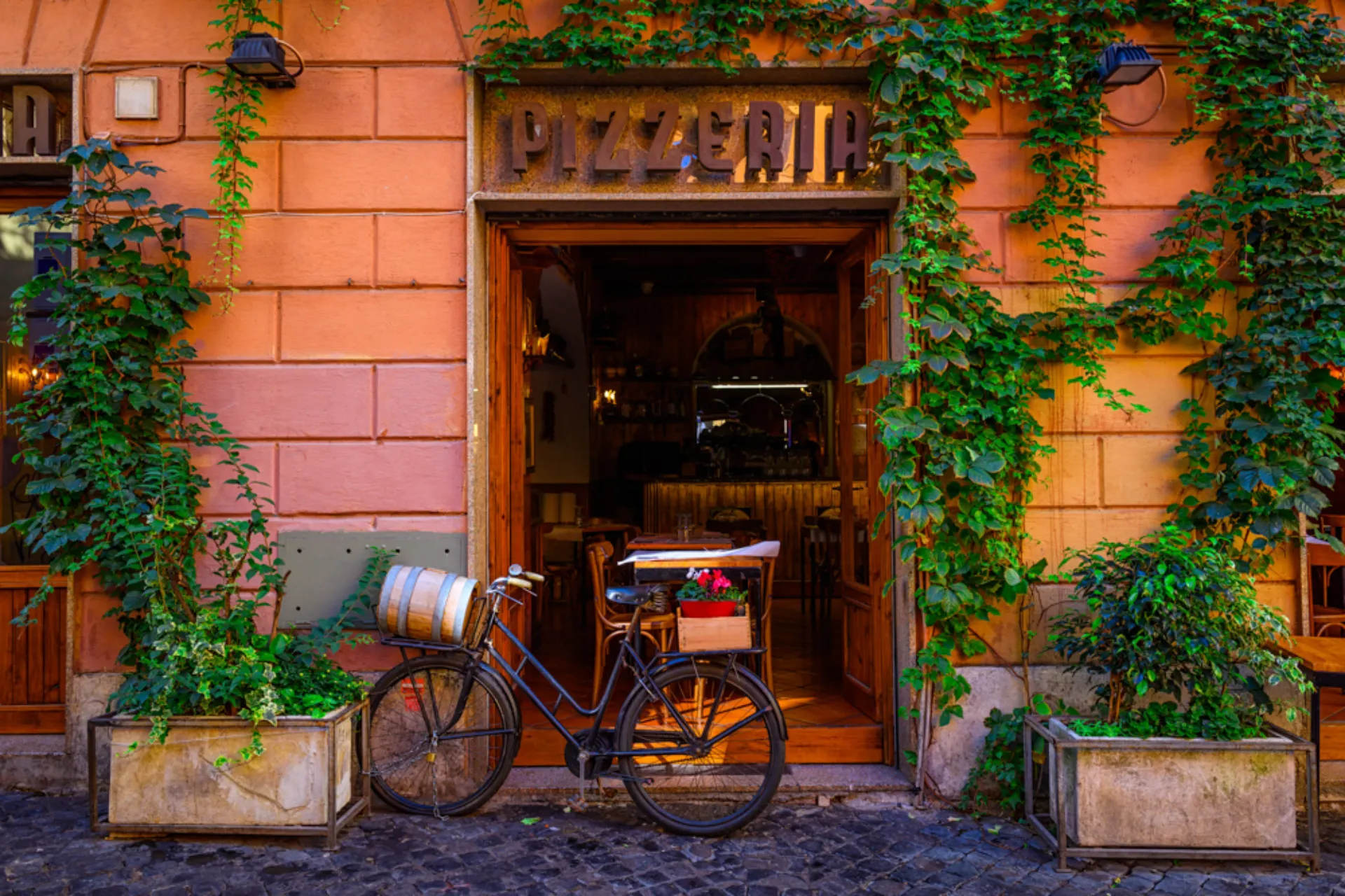 Klimatyczna ulica w rzymskiej dzielnicy Trastevere z wejściem do klasycznej włoskiej pizzerii Klimatyczna ulica w rzymskiej dzielnicy Trastevere z wejściem do klasycznej włoskiej pizzerii