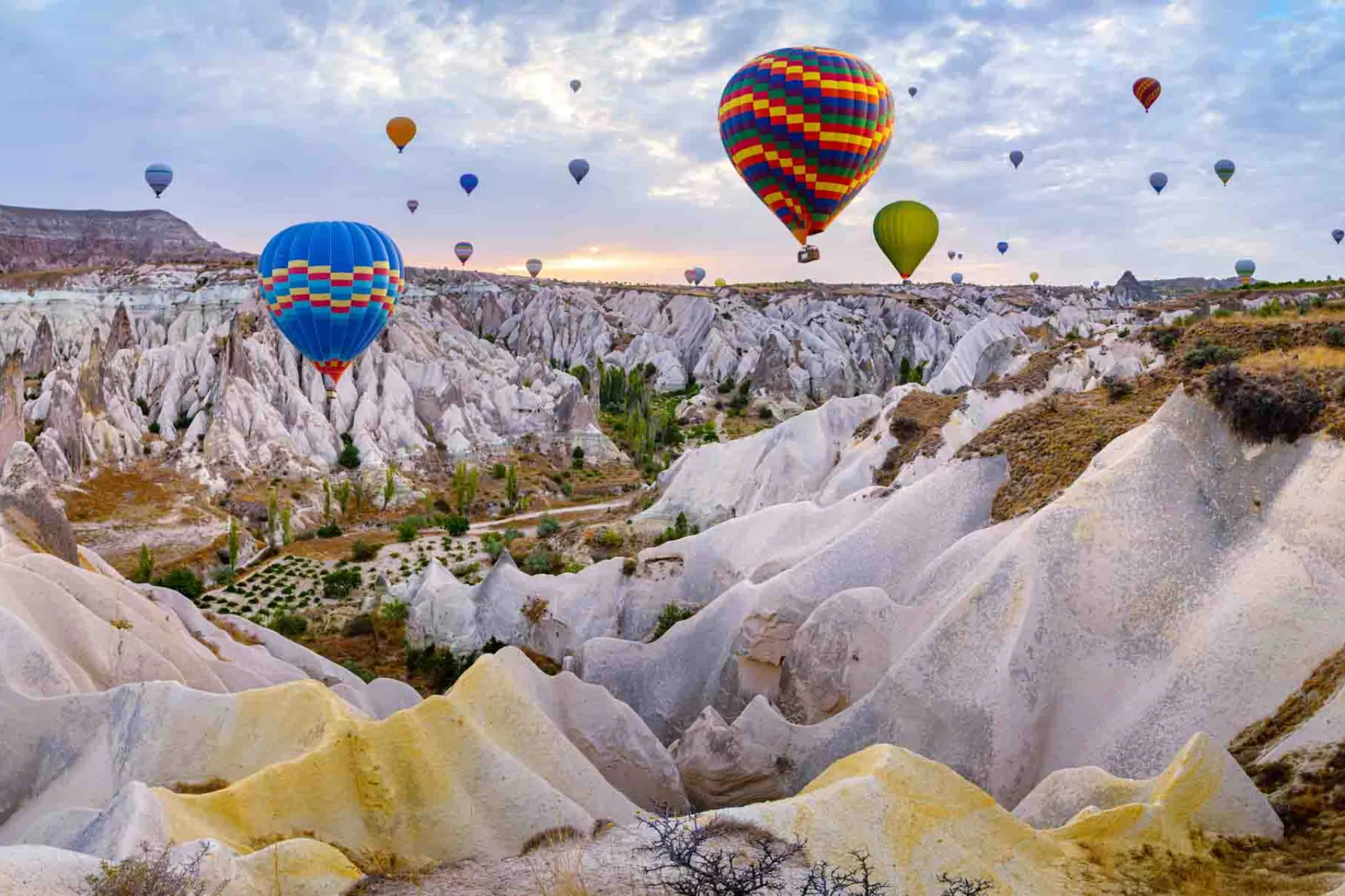 Balony na gorące powietrze unoszą się nad unikalnymi formacjami skalnymi w Kapadocji