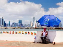 Sprzedawca uliczny odpoczywa w cieniu z widokiem na panoramę Panamy