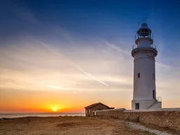 Zachód słońca przy latarni w parku archeologicznym w Paphos