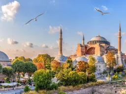 Hagia Sofia w Stambule skąpana w wieczornym słońcu, otoczona minaretami i zielonymi drzewami
