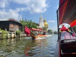 Rejs kanałem w Bangkoku z wielkim złotym Buddą i białą stupą w tle Rejs kanałem w Bangkoku z wielkim złotym Buddą i białą stupą w tle