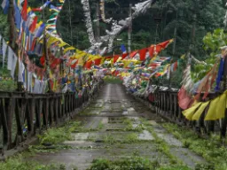 Wiszący most z kolorowymi flagami modlitewnymi - wygląda na trochę zużyty Wiszący most z kolorowymi flagami modlitewnymi - wygląda na trochę zużyty