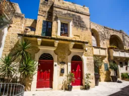 Urocze kamienne domy z czerwonymi drzwiami w Victorii na Gozo Urocze kamienne domy z czerwonymi drzwiami w Victorii na Gozo