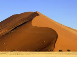 Jedna z kultowych czerwonych wydm Sossusvlei majestatycznie wznosi się ku czystemu niebu Jedna z kultowych czerwonych wydm Sossusvlei majestatycznie wznosi się ku czystemu niebu