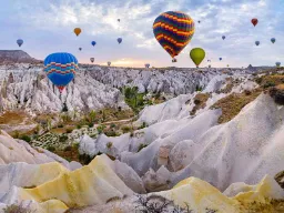 Balony na gorące powietrze unoszą się nad unikalnymi formacjami skalnymi w Kapadocji