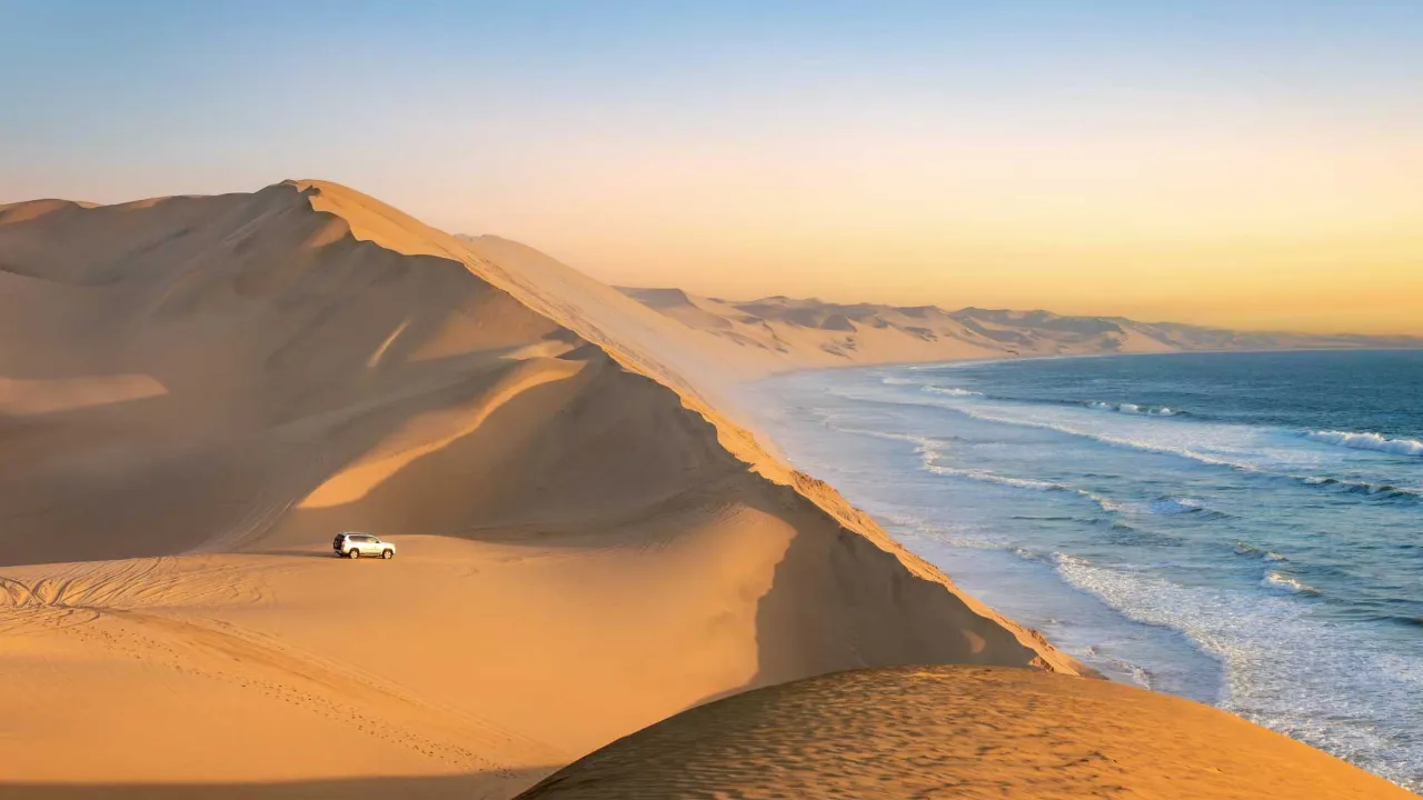 Sandwich Harbour w Namibii, gdzie wysokie wydmy opadają bezpośrednio do morza Sandwich Harbour w Namibii, gdzie wysokie wydmy opadają bezpośrednio do morza